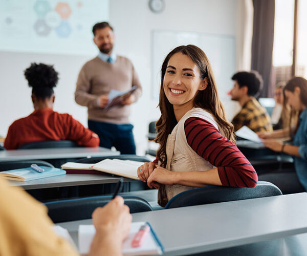 Happy college student during a lecture in the classroom looking at camera.